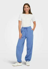 Blå bomuldsjoggers med elastisk talje og snøre, parret med en kortærmet hvid t-shirt og hvide sneakers.