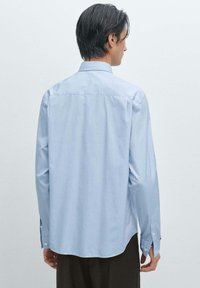 Lichtblauw button-up overhemd van katoen, met een klassieke kraag, lange mouwen en een gebogen zoom. Gladde textuur met subtiele glans.