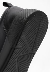 Black leather shoe sole with textured rubber grip and detailed tread pattern shown at an angled close-up view.