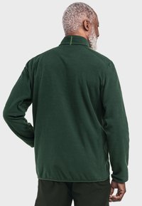Grüne Fleece-Jacke mit Kragen, langen Ärmeln und einer strukturierten Oberfläche. Auffälliges Detail: kontrastierende Nähte am Kragen.