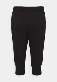 Svarta nedklippta joggingbyxor av mjukt tyg. Har bred elastisk midjeresår och åtsittande muddar. Enkel, minimalistisk design utan utsmyckningar.