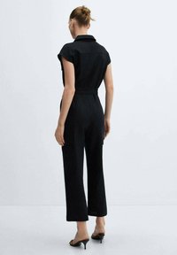 Zwarte jumpsuit met korte mouwen, ceintuur op de taille en cargozakken, met een getailleerde pasvorm en rechte pijpen.