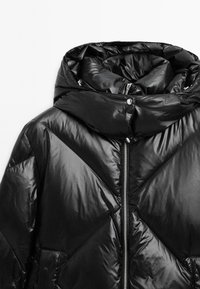 Black puffer jacket with a high collar, featuring a zipper closure and glossy, quilted surface. Distinct geometric stitching pattern.
