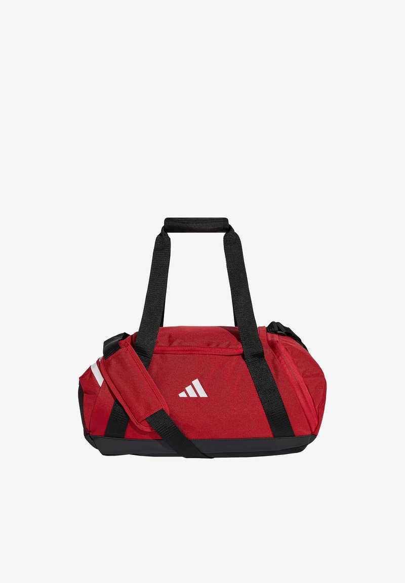 Κόκκινη τσάντα duffel Adidas με μαύρα ρυθμιζόμενα λουριά και λευκό λογότυπο στην μπροστινή πλευρά, σχεδιασμένη για αθλητική ή ταξιδιωτική χρήση.