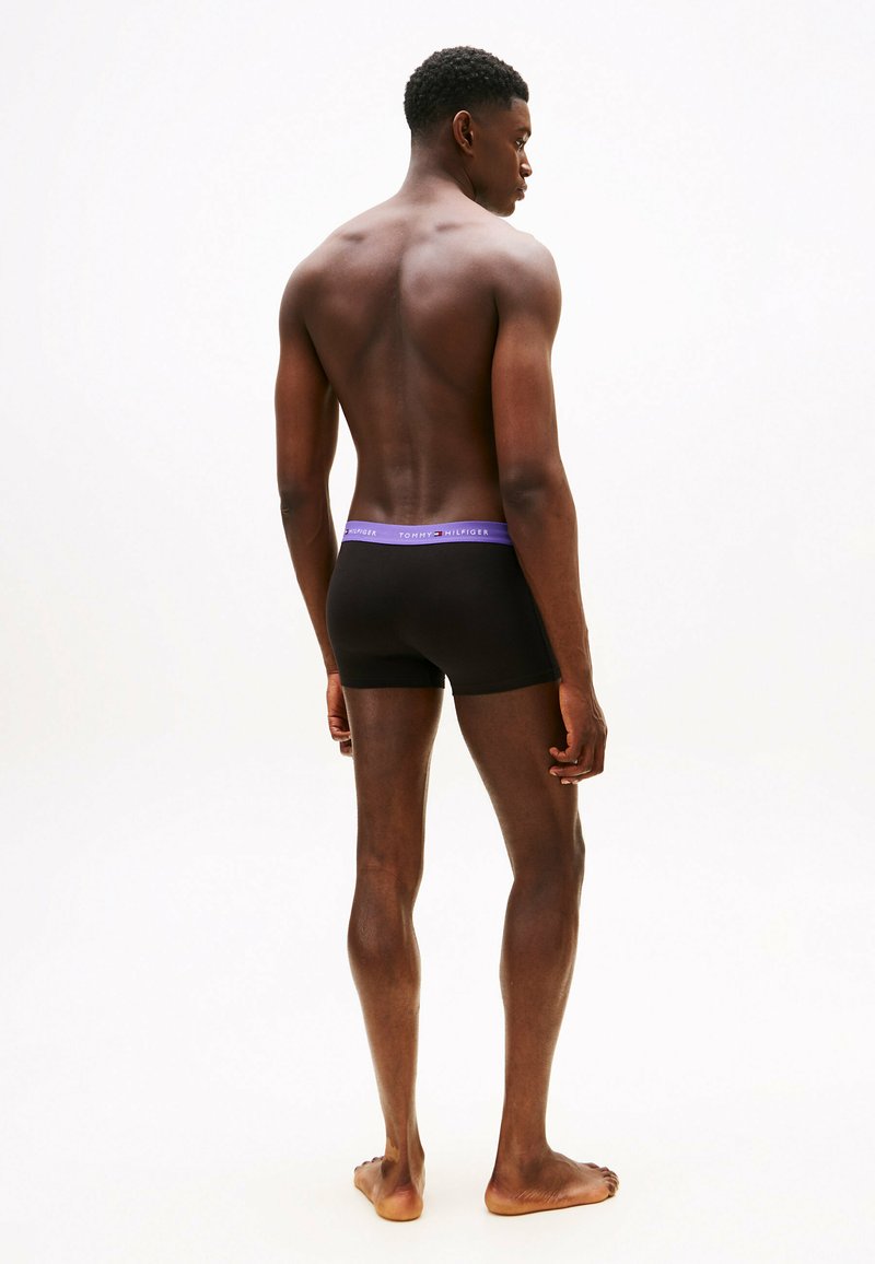 Boxer-briefs noirs avec une taille violette. Le tissu semble lisse et bien ajusté, sans motifs ni logos visibles.