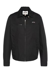Black jacket made from cotton blend, featuring a collar, front zipper, and a chest pocket. Schott logo on the left side. Classic design.