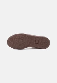 Καφέ λαστιχένια σόλα παπουτσιού με υφή λαβής και ένα τετράγωνο λογότυπο κοντά στη φτέρνα σε ανοιχτό γκρι φόντο.