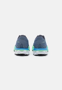 Zapatillas deportivas azules con un upper texturizado, una entresuela verde y azul, y una suela blanca con un patrón de olas distintivo.