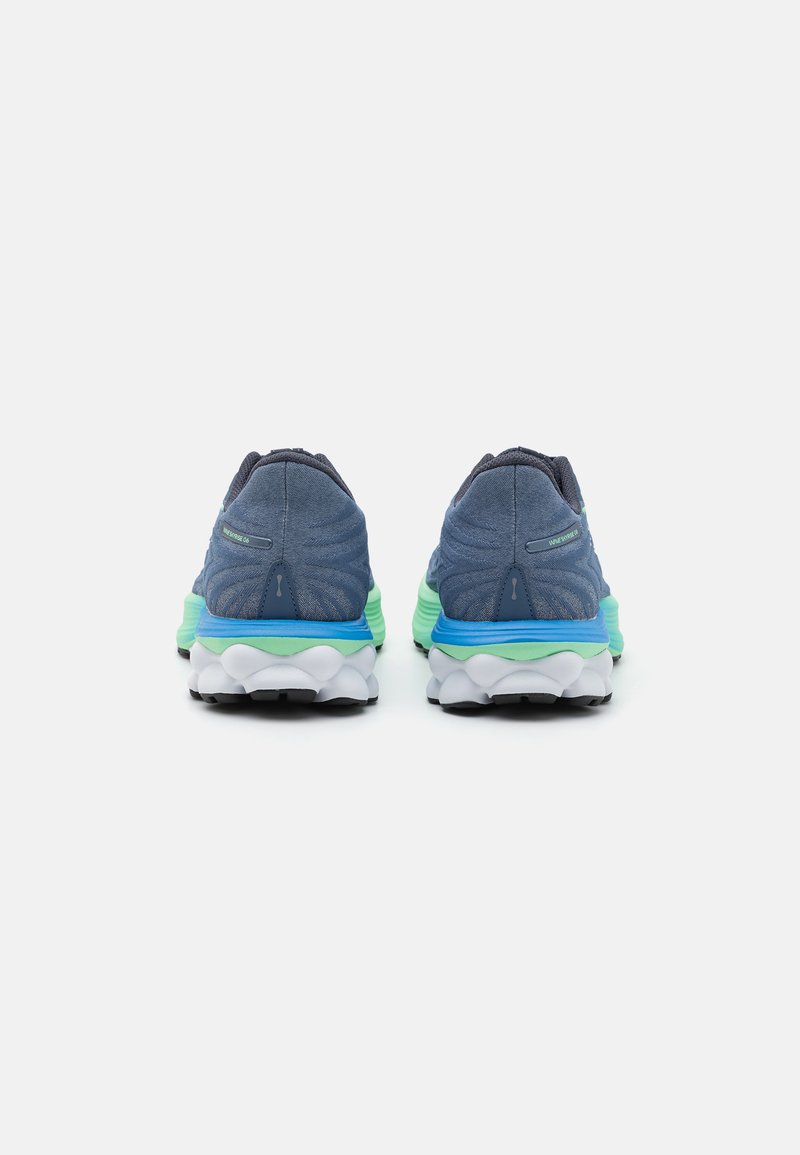 Niebieskie buty sportowe z teksturowaną cholewką, zielono-niebieską podeszwą środkową i białą podeszwą zewnętrzną z charakterystycznym wzorem fal. 