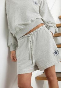 Heledad hall sweatshirt ja sellele sobivad lühikesed püksid pehmest kangast. Pükstel on elastne vöökoht ja logoprint.