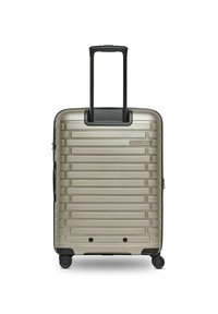 Valigia rigida di colore oro metallizzato, con un design rigato, manico nero retrattile e quattro ruote nere per la mobilità.