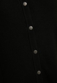 Cardigan nero lavorato a maglia con texture a coste, dotato di cinque bottoni metallici a strisce sul davanti per la chiusura.