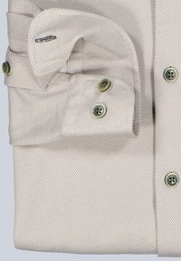 Hellbeige Hemd mit dünnen diagonalen Streifen, gefalteter Manschette, die zwei Knöpfe zeigt, und einer geknöpften Ärmelschlitz.