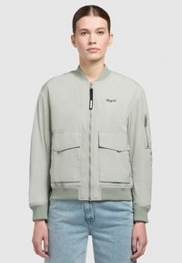 Jachetă bomber gri deschis cu manșete și tiv ribbed, fermoar frontal, două buzunare mari în față și un buzunar lateral. Branding pe piept.