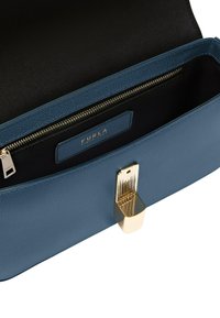 Intérieur d'un sac à main en cuir texturé bleu, avec une doublure noire et un fermoir en métal doré. Comprend une poche zippée avec étiquette de marque.