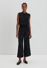 Sleeveless, collared jumpsuit in dark navy with green vertical stripes; loose fit with an elastic waistband; cropped wide-leg trousers.