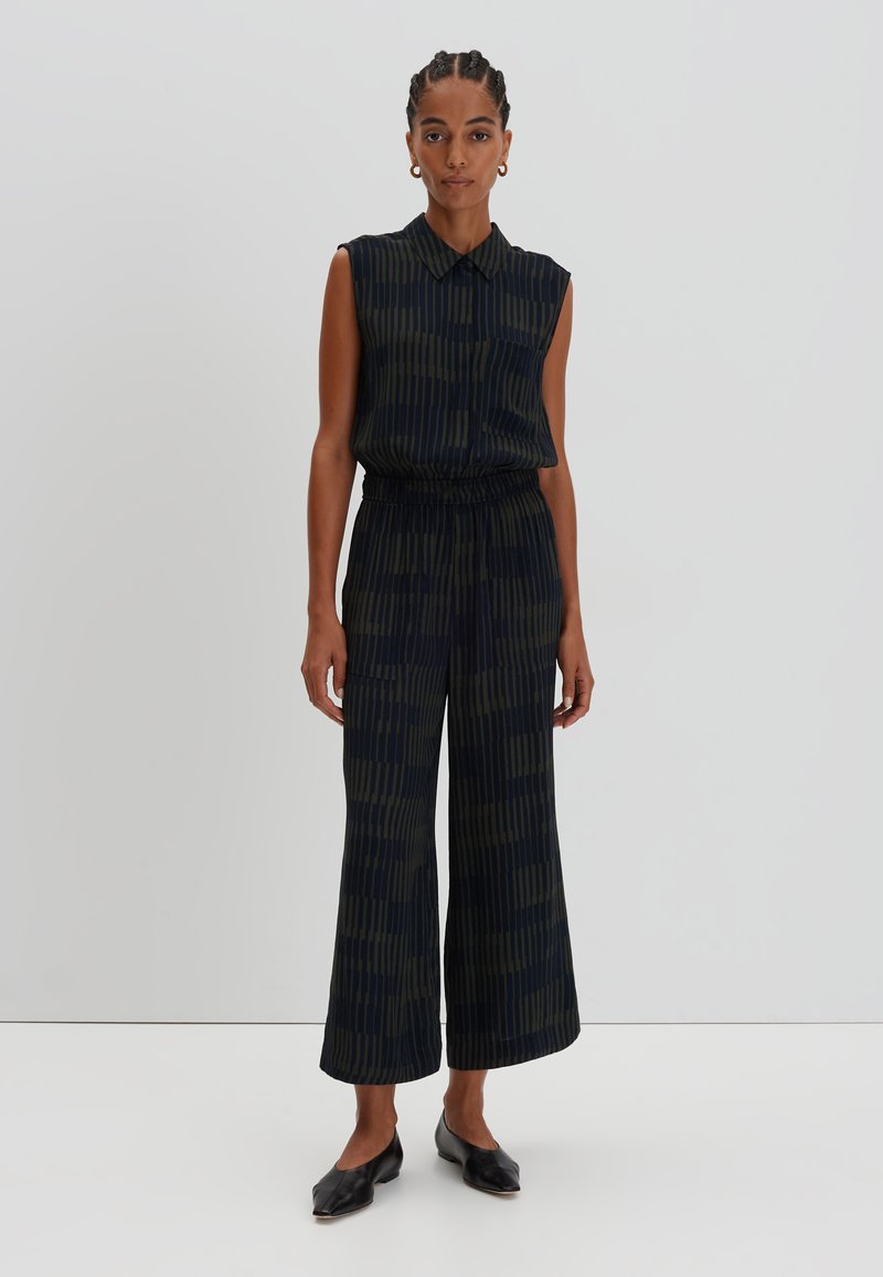 Sleeveless, collared jumpsuit in dark navy with green vertical stripes; loose fit with an elastic waistband; cropped wide-leg trousers.