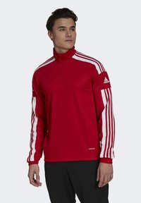 Red long-sleeve athletic top with a high collar, featuring white stripes on the shoulders and sleeves. Includes a quarter-length zipper and logo.