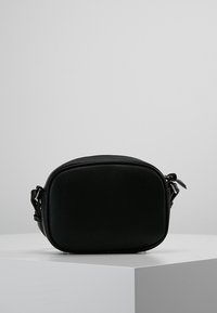 Černá kožená kabelka přes rameno s zaobleným obdélníkovým tvarem, hladkou texturou, nastavitelným popruhem a jemným šitím.