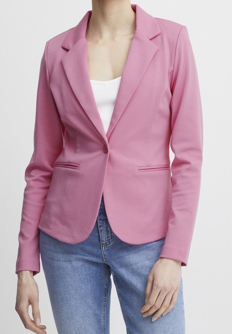 Pink blazer with a notched collar, single button closure, and two side pockets. Made of smooth fabric, fitted design, paired with jeans.