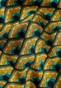 Tekstiili, jossa on aaltoileva kuvio maanläheisissä sävyissä vihreästä, oranssista ja mustasta, vastakkaisilla korostuksilla, luoden tekstuurisen muotoilun.