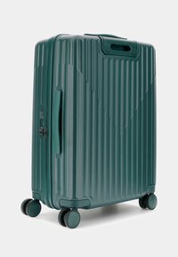 Valigia rigida con rotelle di un profondo teal, caratterizzata da una texture a righe verticali, manico superiore, lucchetto integrato e quattro ruote nere.