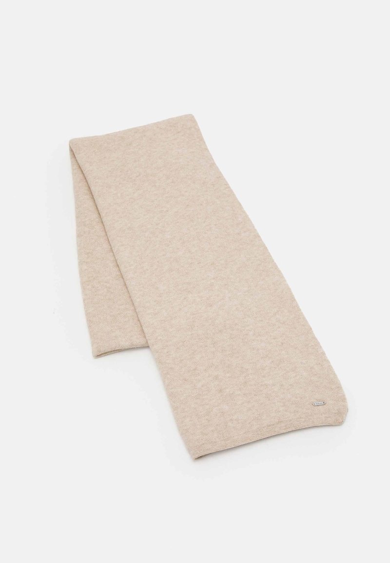 Écharpe beige en tricot pliée sur un fond blanc avec une petite étiquette de marque métallique rectangulaire à une extrémité.