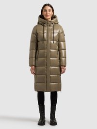 Abrigo acolchado en verde oliva, con capucha, bolsillos con cremallera y diseño acolchado. Combinado con pantalones ajustados negros y botas negras gruesas.