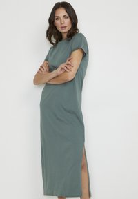 Short-sleeve, teal maxi dress in soft fabric. Features a straight cut with side slits for ease of movement. Simple, minimalist design.