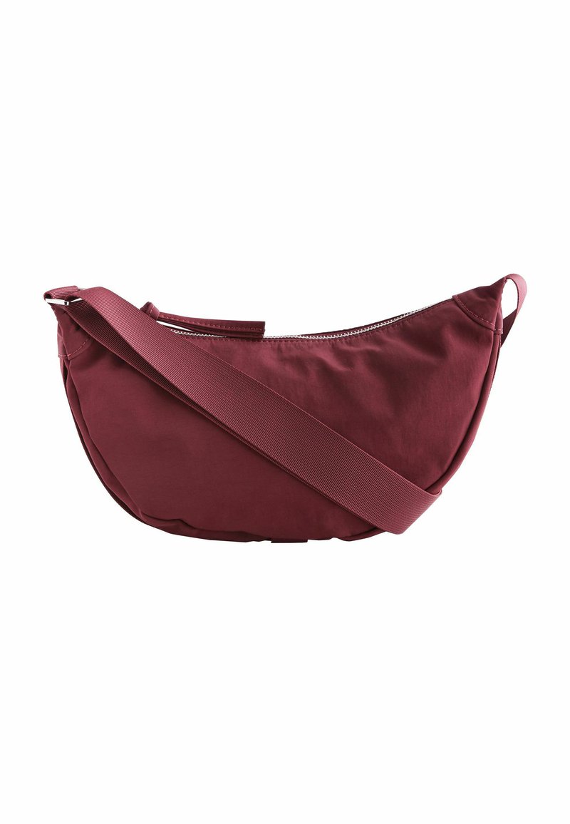 Bordeaux farvet stof skuldertaske med en buet form, lynlåslukning og en bred justerbar rem. Glat tekstur, minimalistisk design.