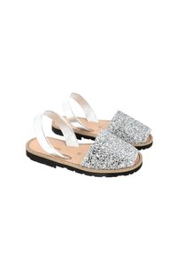Sandali glitter argento con suola piatta in gomma nera, cinghie in pelle e punta scintillante, dotati di soletta imbottita per il comfort.