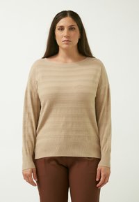 Maglione beige a maniche lunghe con trama a strisce orizzontali. Materiale morbido e leggero, con vestibilità ampia e scollatura a barca. Abbinato a pantaloni marroni.