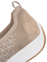 Nahaufnahme eines beigen Slip-On-Sneakers mit gestricktem Stoff, Wildlederferse, geometrischem Strassdesign, weißer Sohle und braunem Gummiaußensohle.