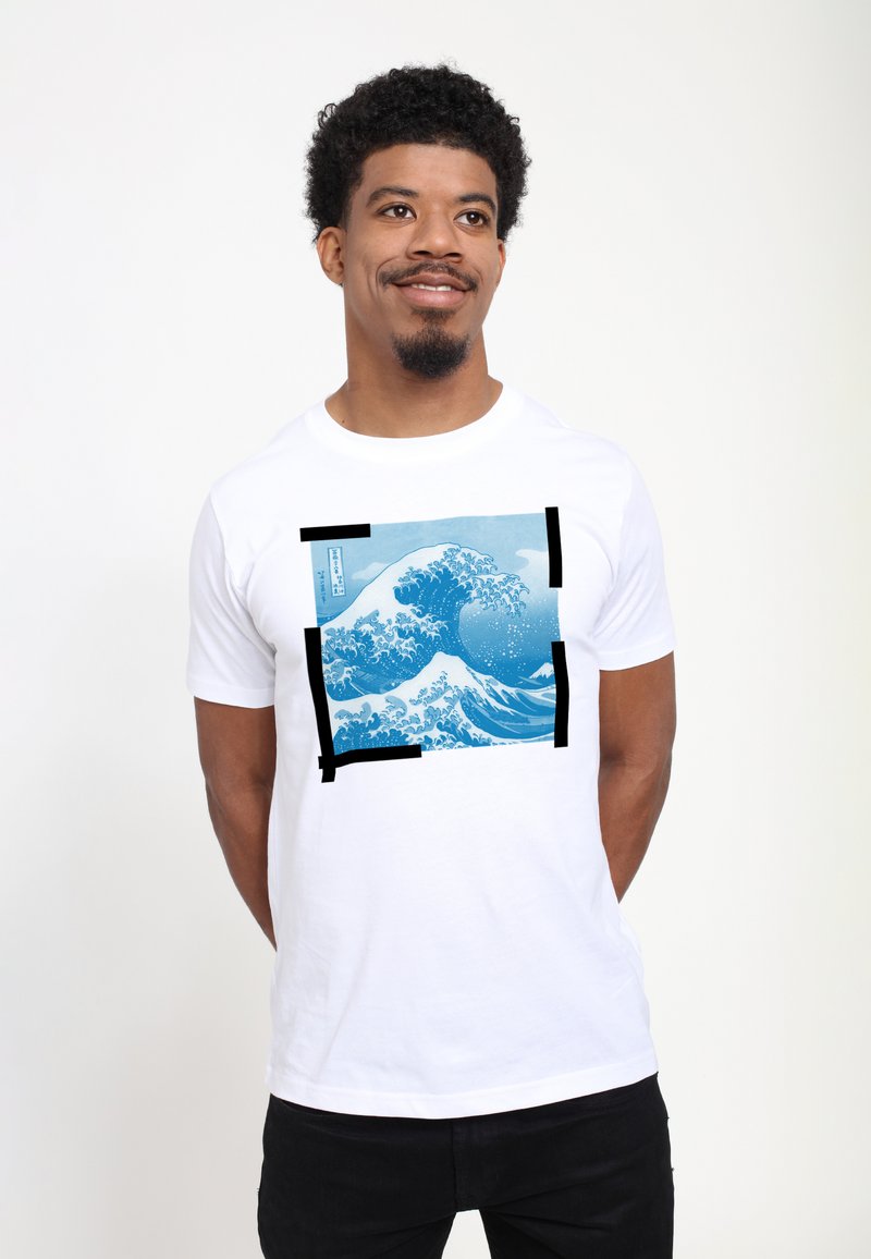 Hvid bomulds T-shirt med et blåt bølgemønster indrammet af sorte firkanter. Designet indeholder detaljerede bølgemønstre og indviklede detaljer.