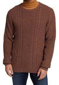 Brauner Strickpullover mit strukturiertem Muster und Zopfmuster, Rundhalsausschnitt und langen Ärmeln. Über einem hellen Rollkragenpullover getragen.