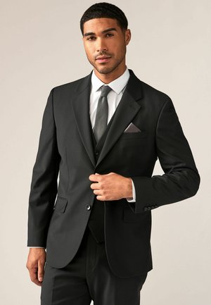Schwarze Anzugjacke mit Revers, Ein-Knopf-Verschluss und zwei seitlichen Taschen, kombiniert mit einem weißen Hemd und einer grauen Krawatte.