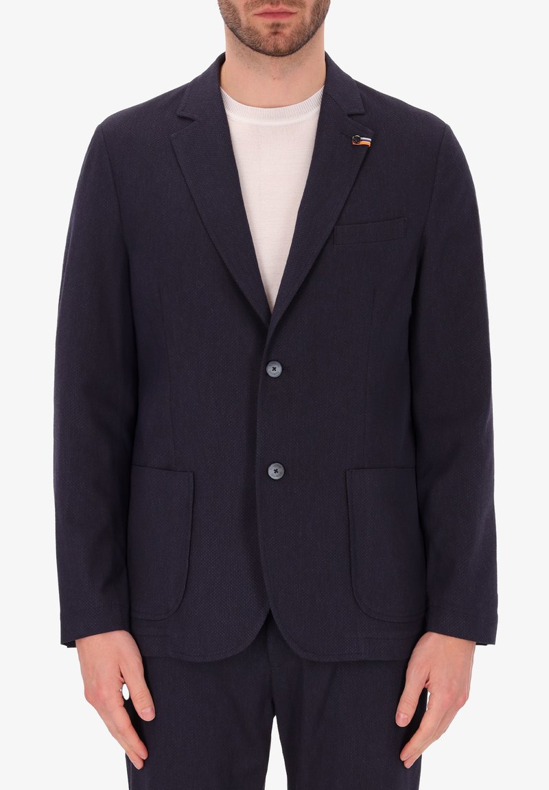 Blazer di un blu navy scuro realizzato in tessuto strutturato, dotato di due tasche frontali, una tasca sul petto e due bottoni. Stile casual con rever a punta.