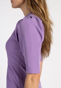 Lila Kurzarmkleid mit tailliertem Oberteil, glatter Textur und Nahtdetails, von der Seite gezeigt.