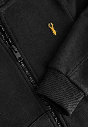 Schwarze Zip-Hoodie aus weichem Stoff, mit gerippten Bündchen und einem kleinen gelben gestickten Hummer-Logo auf der Brust.