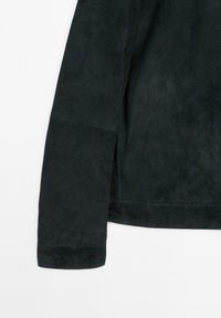 Ärmel einer schwarzen Wildlederjacke mit glatter Textur, gerade geschnitten und mit seitlichen Schlitzen. Die innere Naht ist zum Schutz haltbar genäht.