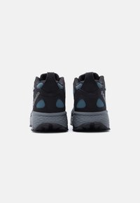 Ζεύγος αθλητικών παπουτσιών Columbia σε μαύρο και μπλε χρώμα που απεικονίζονται από πίσω, με παχύ, γκρι, επενδυμένο πέλμα και λογότυπο στη φτέρνα.