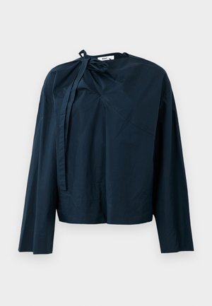 Navy blue long-sleeve top in lightweight fabric, featuring a knot detail at the neckline and asymmetric design elements.