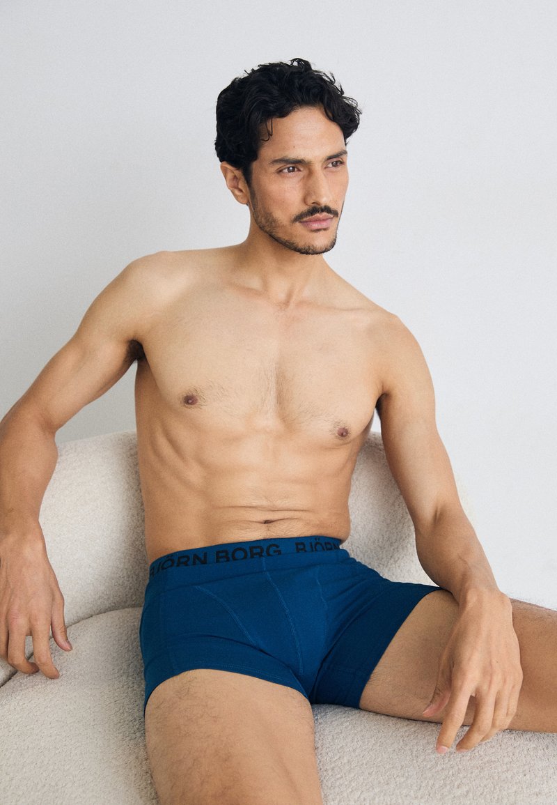 Boxer da uomo blu con elastico nero con la scritta "BJÖRN BORG". Tessuto liscio, design aderente e lunghezza della gamba corta.