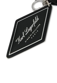 Must mustripsistustkiist lehtinmust histt ger slik lar peinded valgel trükitextist "Karl Lagerfeld" ja "21 RUE ST-GUILLAUME PARIS" koos hõbedase äärega.