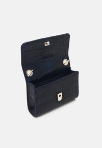 Cartera azul marino con relieve de cocodrilo y textura suave, con herrajes dorados y un cierre de presión cuadrado. Abierta para mostrar los compartimentos interiores.