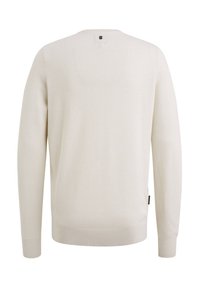 Pull en tricot couleur crème à manches longues, avec poignets et ourlet côtelés, vu de dos avec une petite étiquette près de l'encolure.
