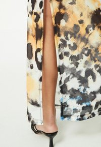 Maxikleid mit Leopardenmuster und einem hohen Schlitz, aus leichtem Stoff in Schwarz, Orange und Blau, nahtloser Saum.