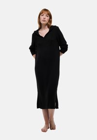 Robe à capuche noire avec des manches longues, un col en V et des fentes sur les côtés. Tissu doux avec une coupe décontractée et un cordon de serrage ajustable à la capuche.