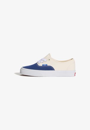 Zapatilla Vans de caña baja con puntera azul y parte superior de lona blanca, cordones blancos y suela de goma blanca con logo rojo en el talón.