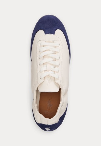 Baskets en cuir blanc avec bout et talon en daim bleu marine, lacets blancs, et logo Polo Ralph Lauren sur la semelle intérieure et le talon.
